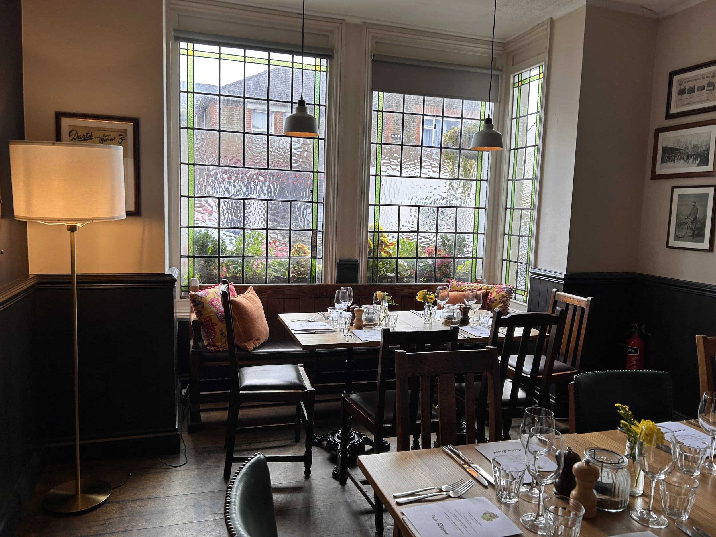 A dining table set beside stained-glass windows in the pub